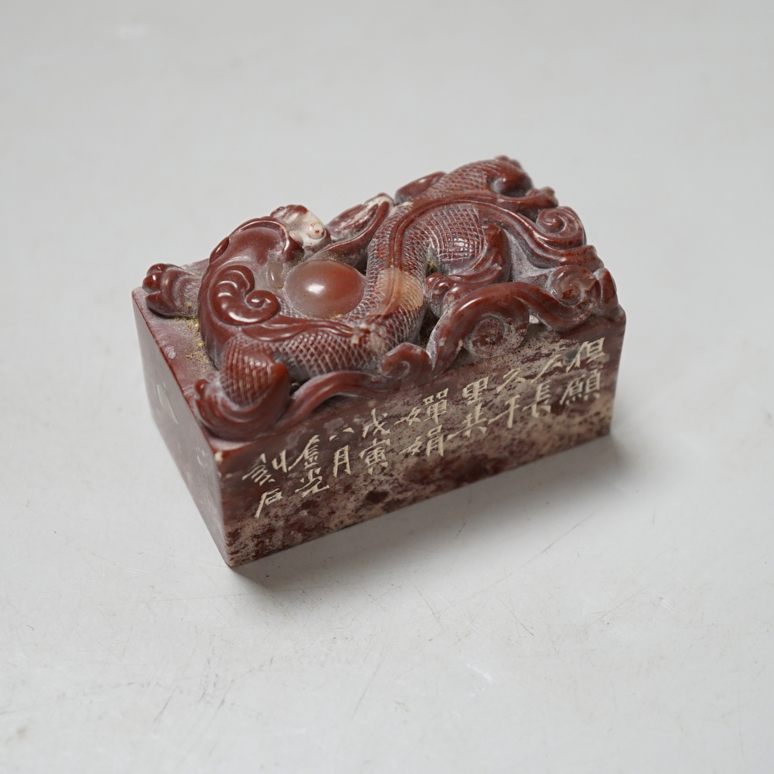 A Chinese chicken’s blood inscribed soapstone seal, carved with a dragon, 6cm